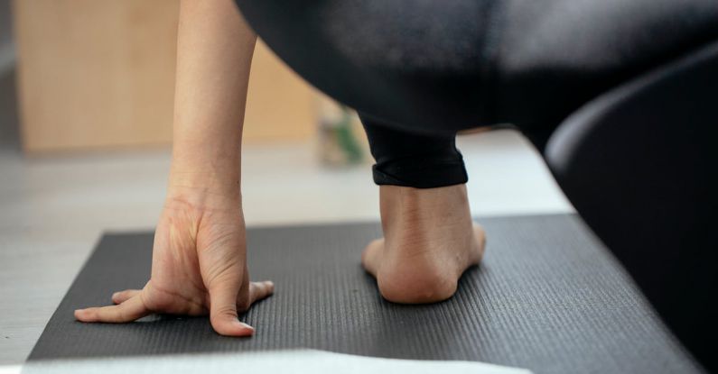 Holistic Approaches - Back view of crop unrecognizable flexible female stretching legs and practicing yoga in Crescent Lunge on the Knee pose at home